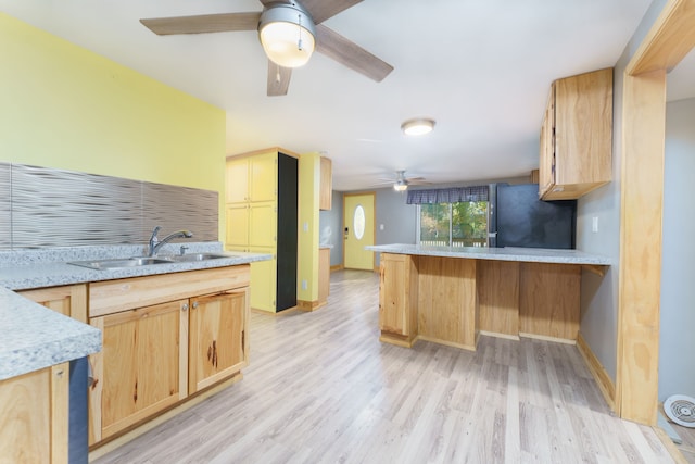 kitchen featuring light brown cabinets, sink, kitchen peninsula, black refrigerator, and light wood-type flooring