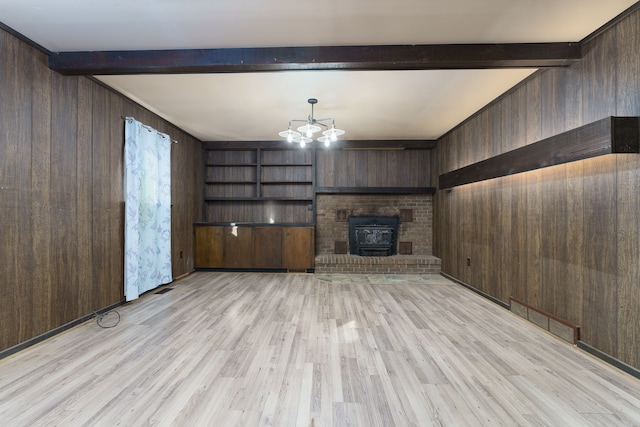 unfurnished living room with a wood stove, light hardwood / wood-style flooring, beam ceiling, and wood walls