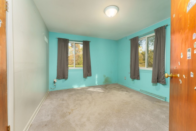 carpeted empty room featuring baseboard heating