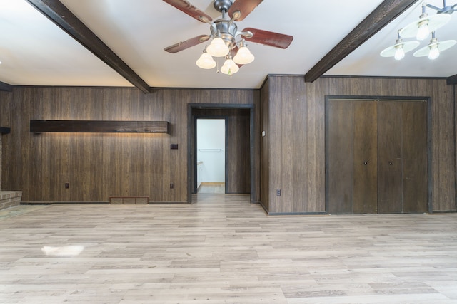 unfurnished room with wooden walls, light hardwood / wood-style flooring, beamed ceiling, and ceiling fan