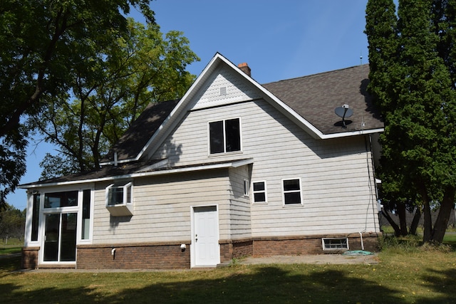 rear view of house featuring a yard and a sunroom