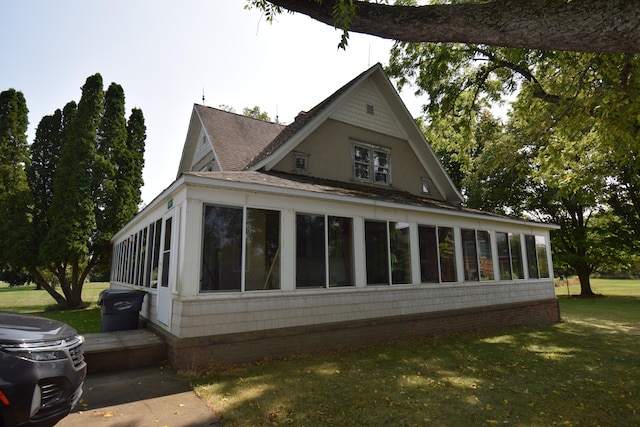 view of property exterior featuring a lawn and a sunroom