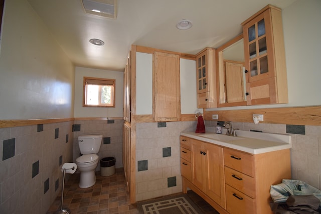 bathroom featuring vanity, toilet, and tile walls