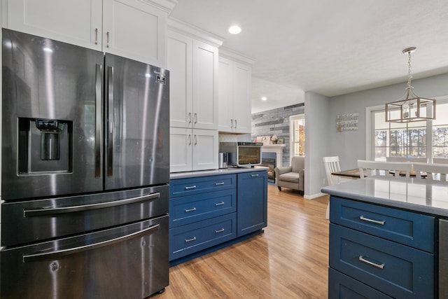 kitchen with white cabinets, stainless steel refrigerator with ice dispenser, a wealth of natural light, and blue cabinetry