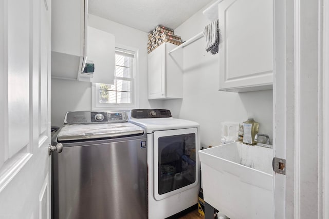 clothes washing area with cabinets, sink, washer and dryer, and a textured ceiling