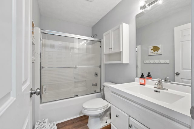 full bathroom featuring hardwood / wood-style floors, vanity, toilet, enclosed tub / shower combo, and a textured ceiling