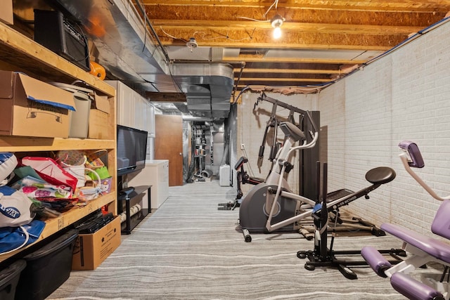 workout room featuring light carpet and brick wall