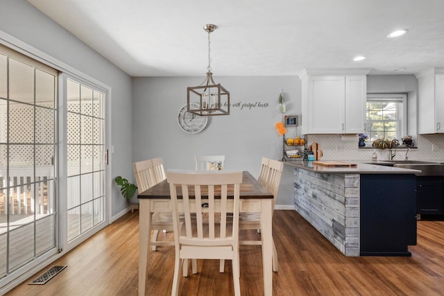 dining room featuring a notable chandelier, sink, and dark wood-type flooring