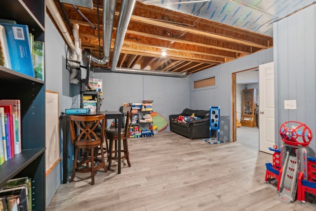 basement with light hardwood / wood-style floors and wood walls