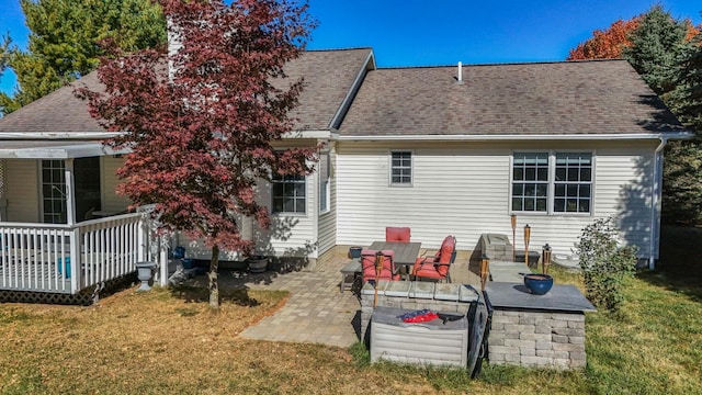 rear view of property featuring a lawn, a deck, and a patio