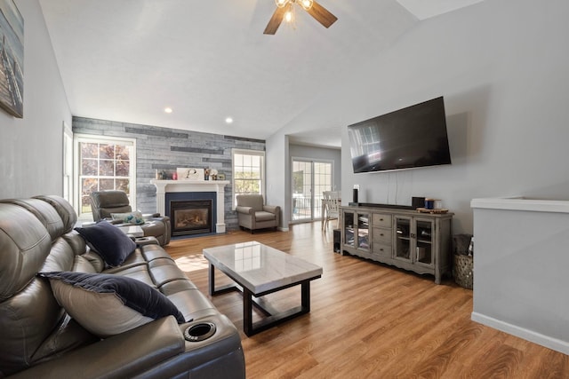 living room with ceiling fan, light hardwood / wood-style floors, and lofted ceiling