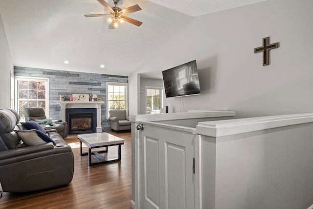 living room with a wealth of natural light, ceiling fan, dark hardwood / wood-style floors, and vaulted ceiling