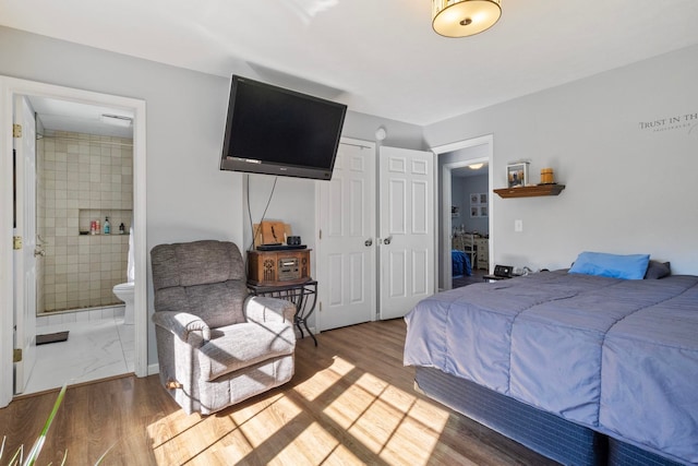 bedroom featuring connected bathroom, hardwood / wood-style flooring, and a closet