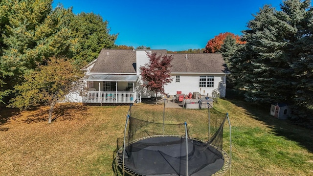 back of house featuring a yard and a trampoline