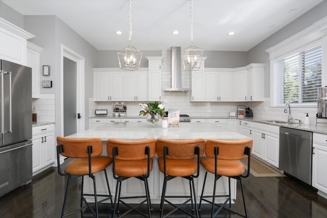 kitchen with wall chimney exhaust hood, white cabinetry, a kitchen island, and stainless steel appliances