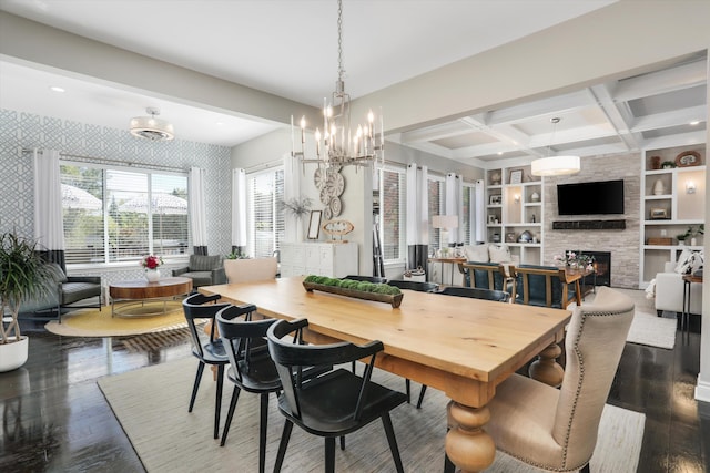 dining area with built in shelves, dark hardwood / wood-style floors, a stone fireplace, and coffered ceiling