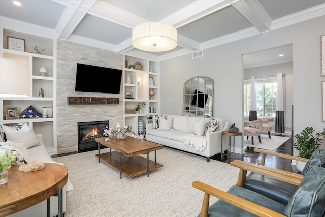 living room featuring coffered ceiling, a stone fireplace, built in shelves, beam ceiling, and wood-type flooring