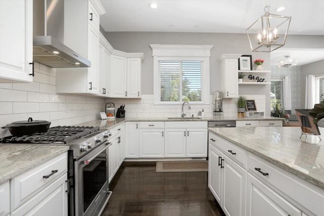 kitchen featuring sink, stainless steel stove, wall chimney exhaust hood, decorative light fixtures, and white cabinetry