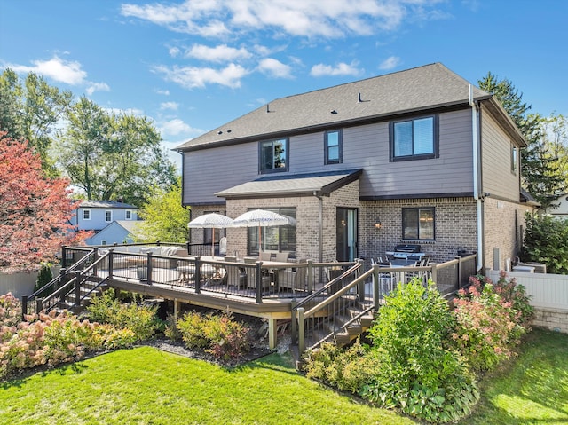 back of property with a deck and a lawn