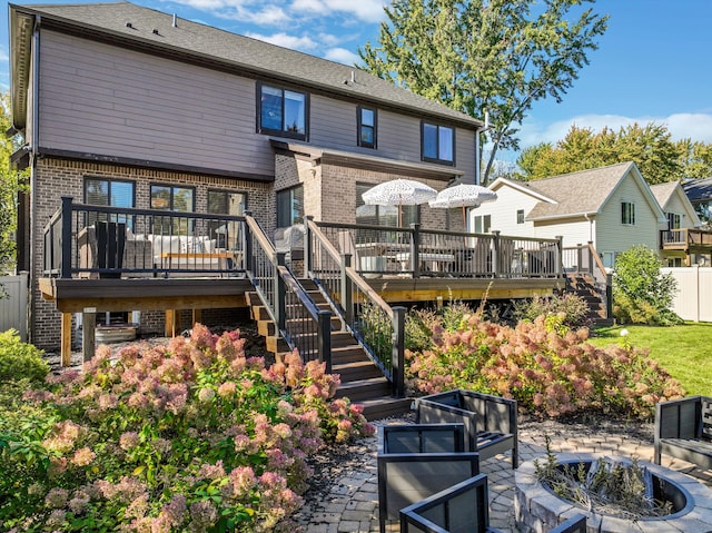 rear view of property with a wooden deck, a patio, and an outdoor fire pit