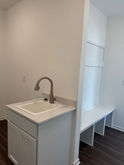 washroom featuring dark wood-style floors, baseboards, and a sink