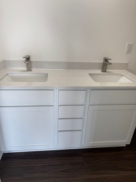 full bathroom with double vanity, a sink, and wood finished floors