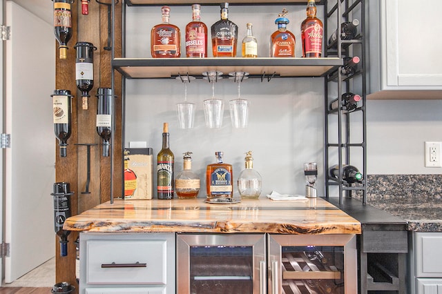 bar featuring dark stone countertops, white cabinetry, light wood-type flooring, and wine cooler