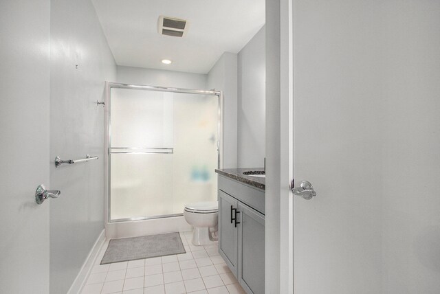 bathroom with tile patterned floors, a shower with door, vanity, and toilet