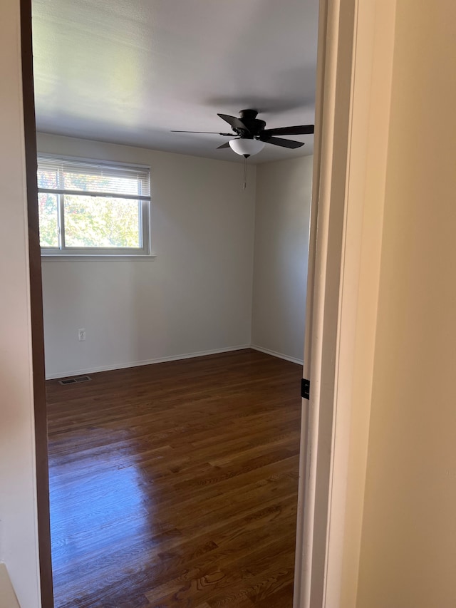 unfurnished room featuring ceiling fan and dark wood-type flooring