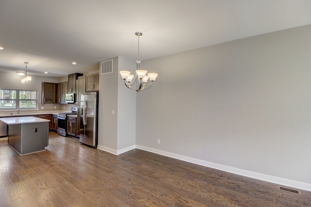 kitchen with a kitchen island, stainless steel appliances, hanging light fixtures, and dark wood-type flooring