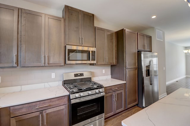 kitchen featuring light stone counters, dark wood-type flooring, and stainless steel appliances