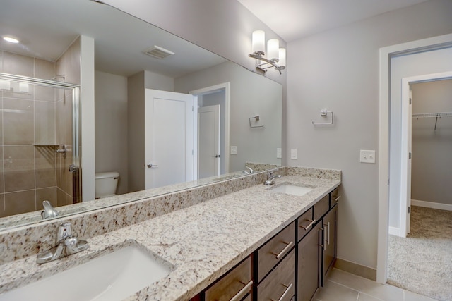 bathroom featuring tile patterned flooring, vanity, a shower with door, and toilet