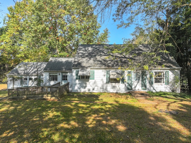 cape cod home featuring a front yard and a wooden deck