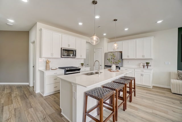 kitchen with light countertops, appliances with stainless steel finishes, a sink, and a kitchen island with sink