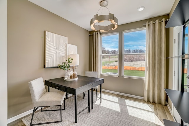 home office with baseboards, light wood-type flooring, and an inviting chandelier