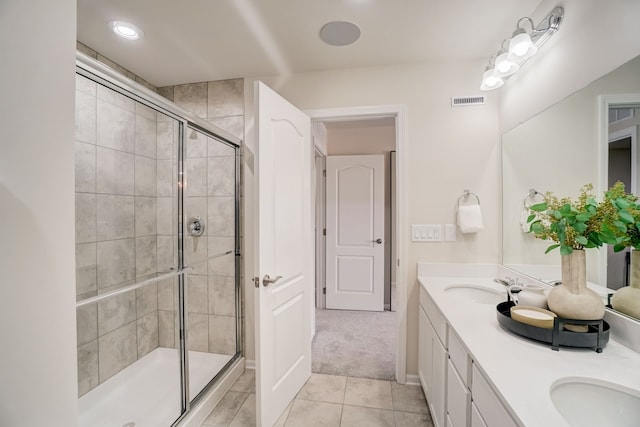 bathroom featuring double vanity, a shower stall, visible vents, and a sink