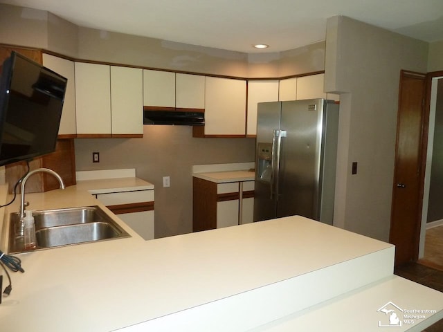 kitchen featuring white cabinetry, kitchen peninsula, stainless steel fridge, and sink