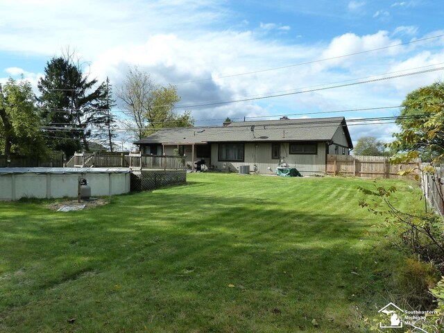 back of house with a yard and a fenced in pool