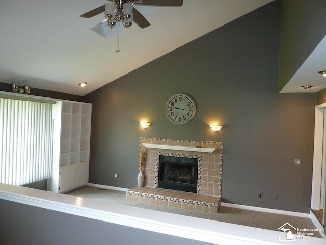 unfurnished living room featuring carpet, vaulted ceiling, ceiling fan, and a tiled fireplace