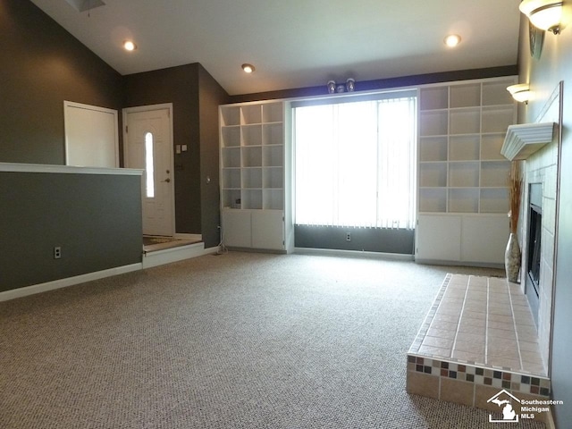 unfurnished living room featuring carpet, lofted ceiling, and a tiled fireplace