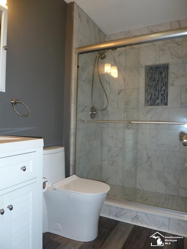 bathroom featuring wood-type flooring, vanity, toilet, and an enclosed shower