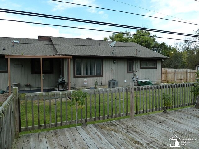 view of front of property with central AC unit, a wooden deck, and a front yard