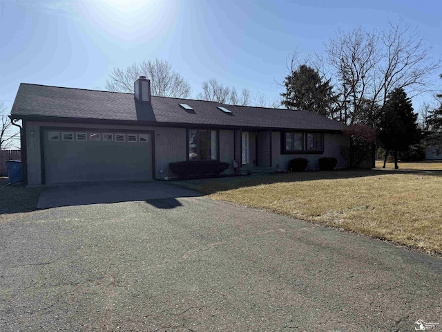 view of front facade with a shingled roof, a front yard, a chimney, a garage, and driveway