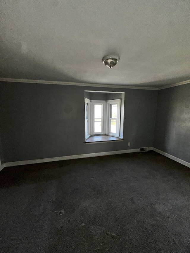 carpeted empty room featuring ornamental molding and a textured ceiling