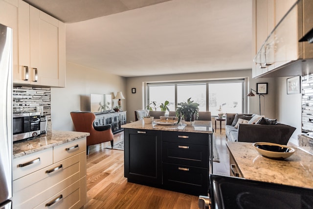 kitchen featuring white cabinets, light hardwood / wood-style floors, light stone countertops, and tasteful backsplash