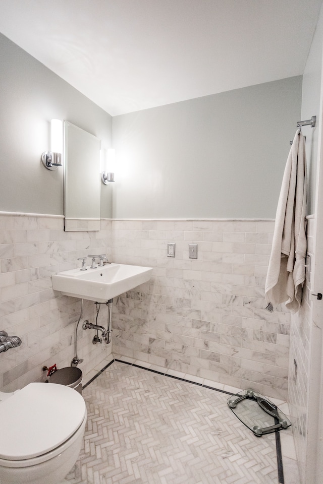 bathroom featuring toilet, tile walls, and sink