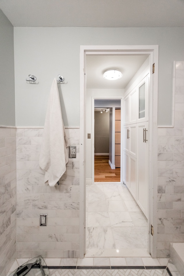 bathroom with wood-type flooring and tile walls