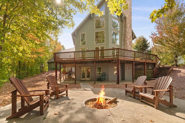 back of property with a deck, an outdoor fire pit, and a patio