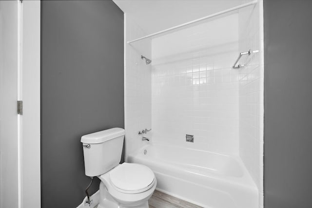 bathroom with hardwood / wood-style flooring, tiled shower / bath combo, and toilet