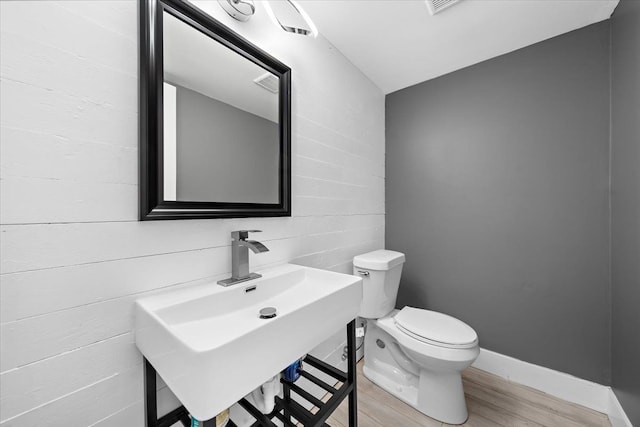 bathroom with hardwood / wood-style flooring, toilet, sink, and vaulted ceiling